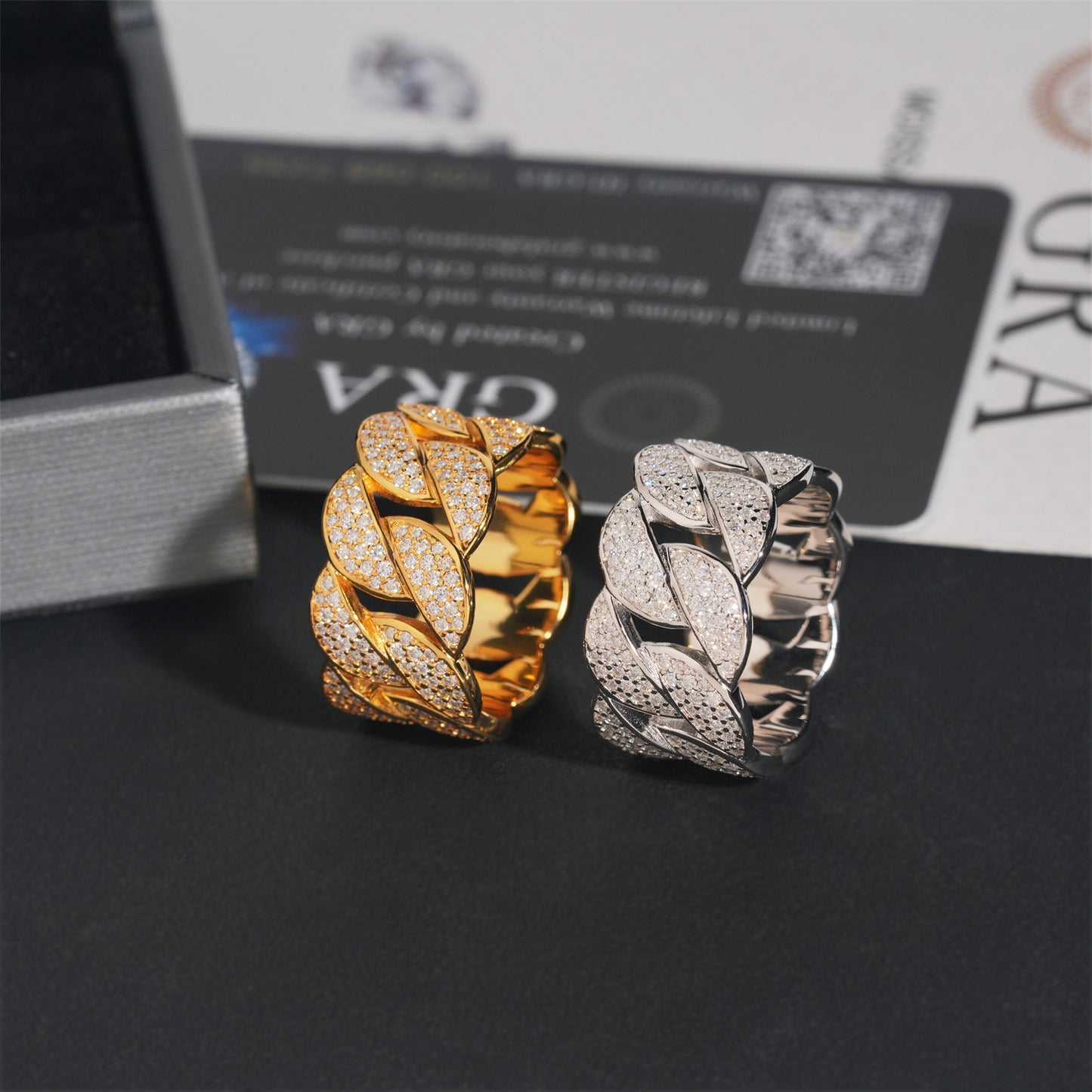 Gold and silver leaf-shaped earrings on a dark surface with a brand box in the background.