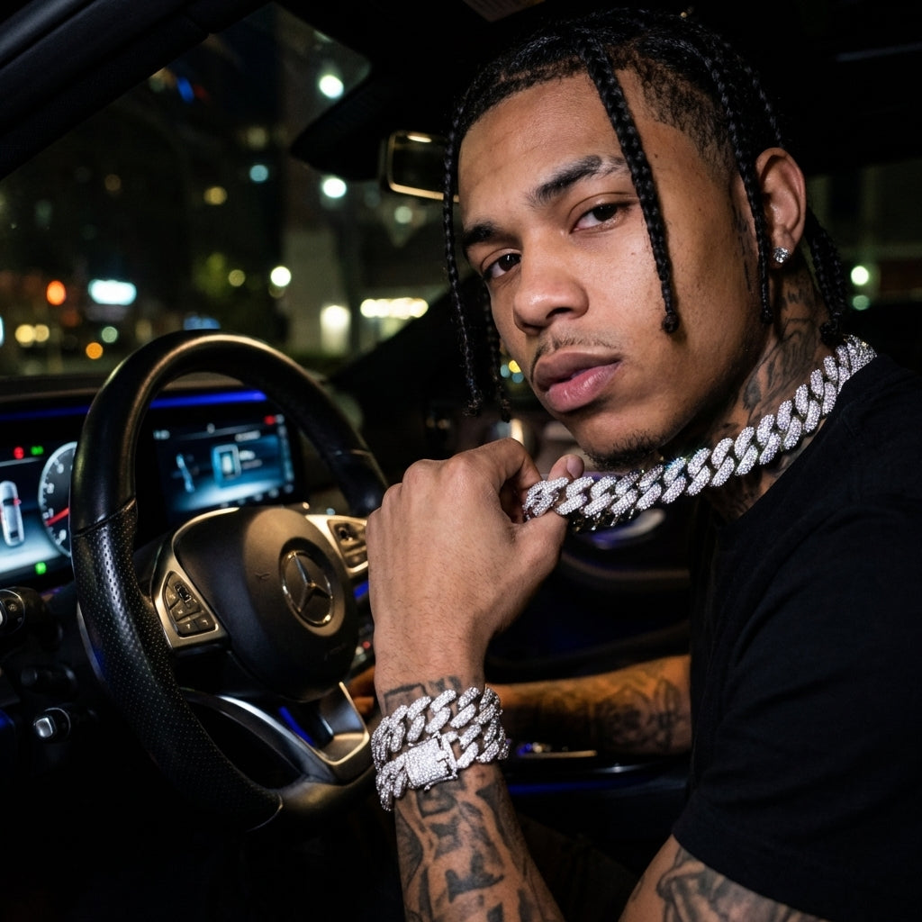 Man with tattoos and a chain necklace sitting inside a car at night.