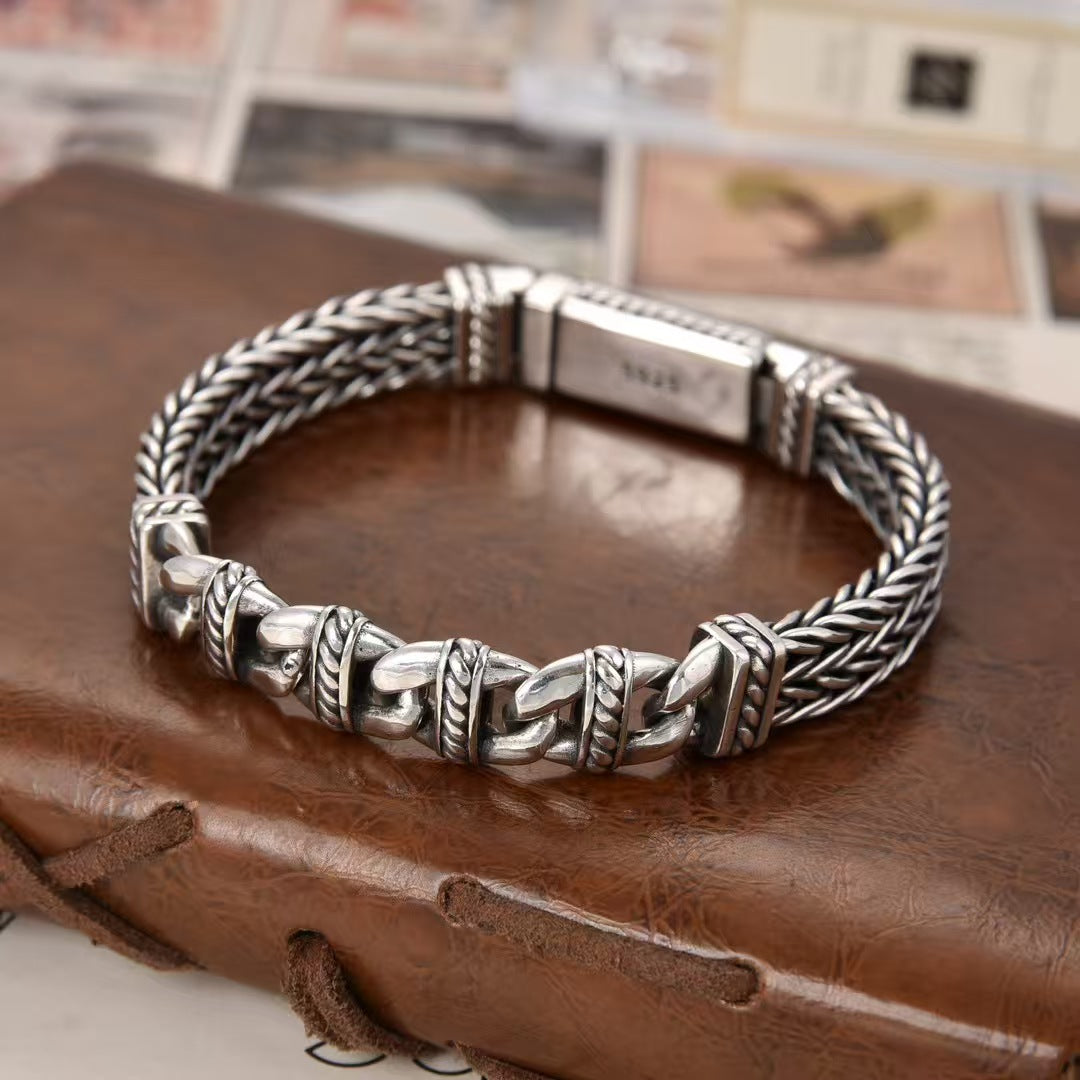 Silver braided bracelet on a brown leather surface