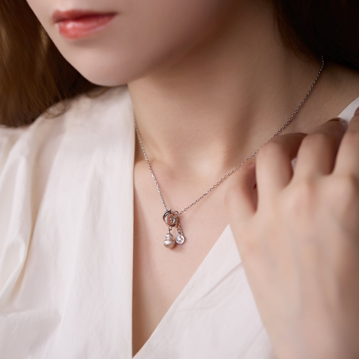 Necklace with a pendant worn by a person in a white outfit