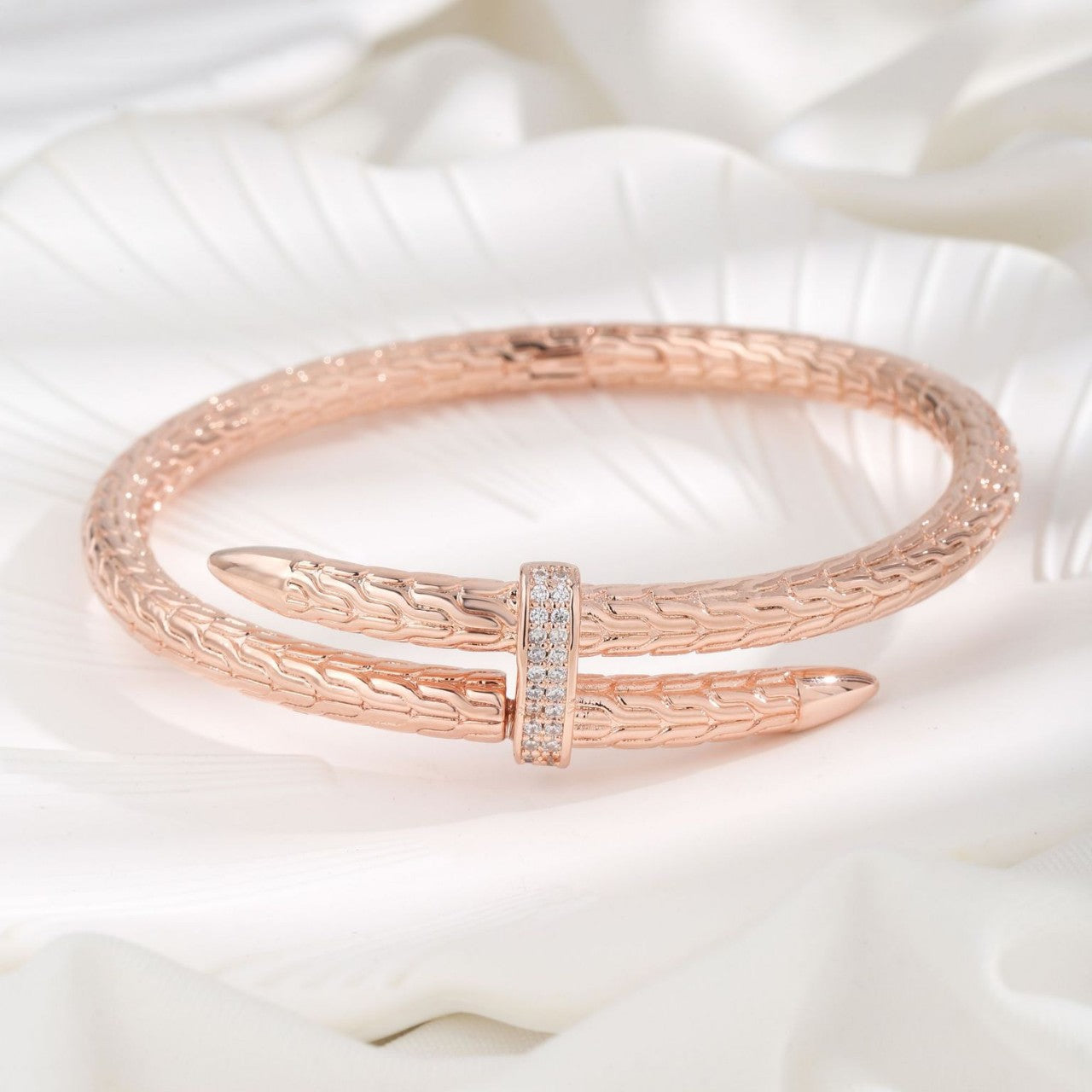 Rose gold bracelet with diamond accents on a white fabric background