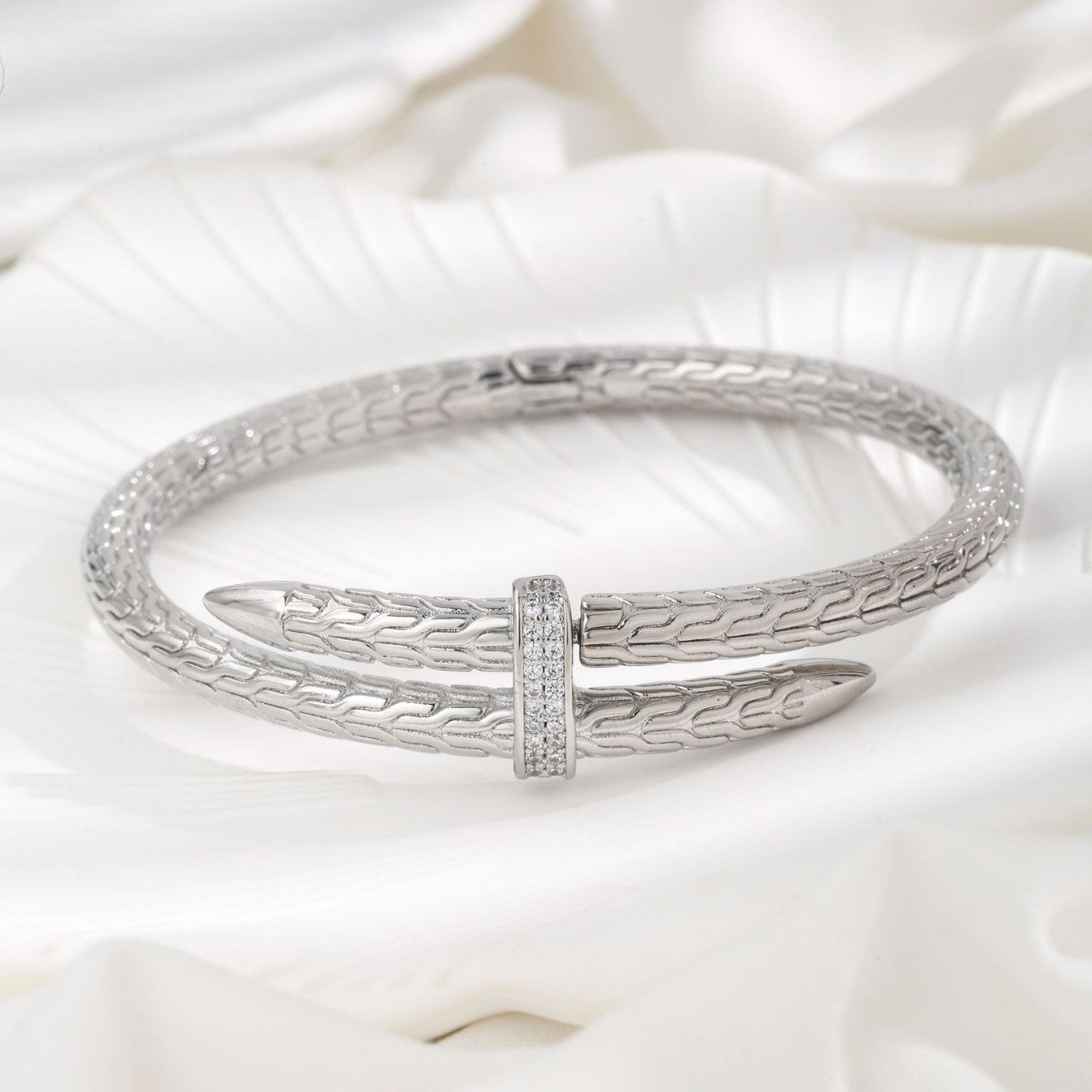 Silver bracelet with a unique design on a white fabric background