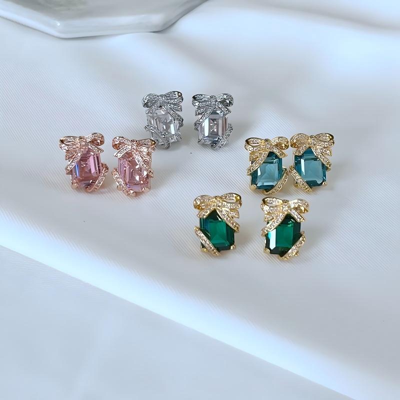 Clean shot of studs on a neutral or festive background (e.g., white marble or dark green velvet), highlighting the gift box shape and green pavé sparkle. Alt: “KATE SPADE Pavé Emerald Present Stud Earrings – Green Gift Box Design.”