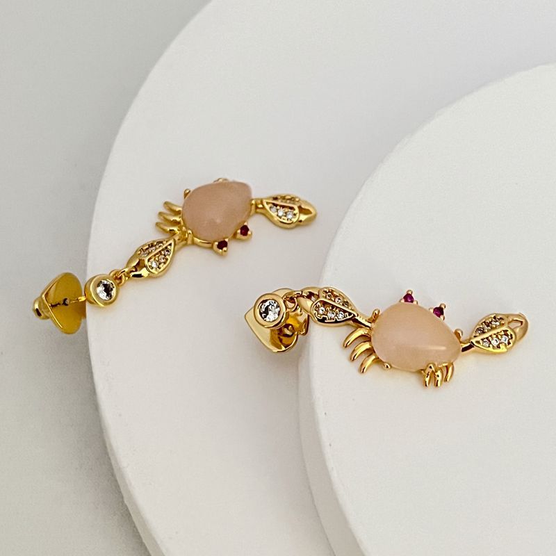 Earrings side by side on sandy-beige background. Alt: “Kate Spade Starfish & Crab Earrings – Pink Crystal Ocean Jewelry.”