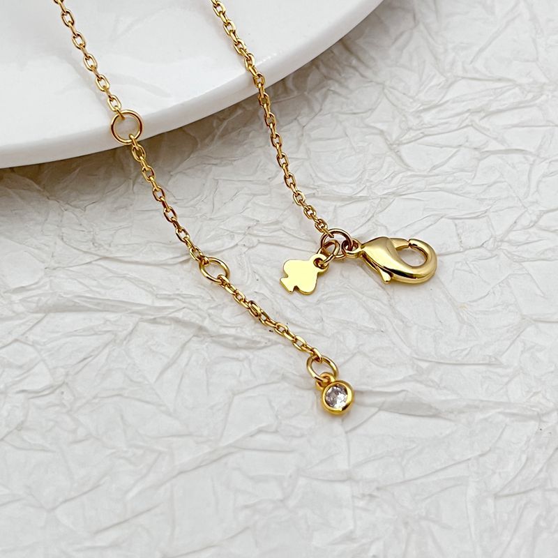 Necklace laid flat on a light neutral background, highlighting the gold setting and vibrant blue/green gemstones. Alt: “Kate Spade Gold Necklace with Blue and Green Gemstones – Colorful Pendant Jewelry.