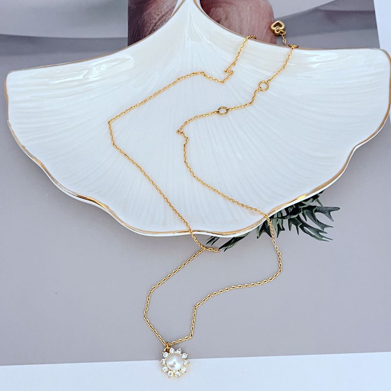 Necklace on a soft, bright background (light blue or creamy white), highlighting the sun pendant's pearl center and crystal halo. Alt: “Kate Spade Sunny Pave & Imitation Pearl Halo Necklace – Radiant Sun Motif Jewelry.”