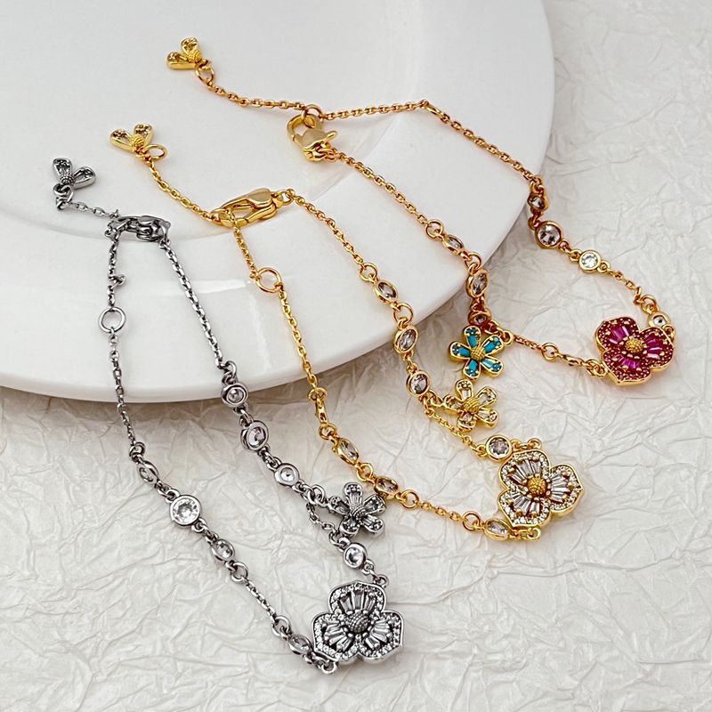 Bracelet displayed on a soft moss green or linen background, highlighting the mix of floral and leaf charms. Alt: “Kate Spade Yellow Gold Plated Flowers & Plants Bracelet – Botanical Charm Jewelry.”