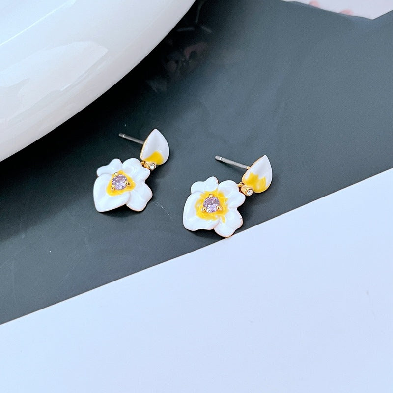 Earrings on a soft lavender or cream background, showcasing the purple and gold pansy blooms with delicate drop findings. Alt: “Kate Spade Precious Pansy Drop Earrings – Enamel Pansy Flower Jewelry.”