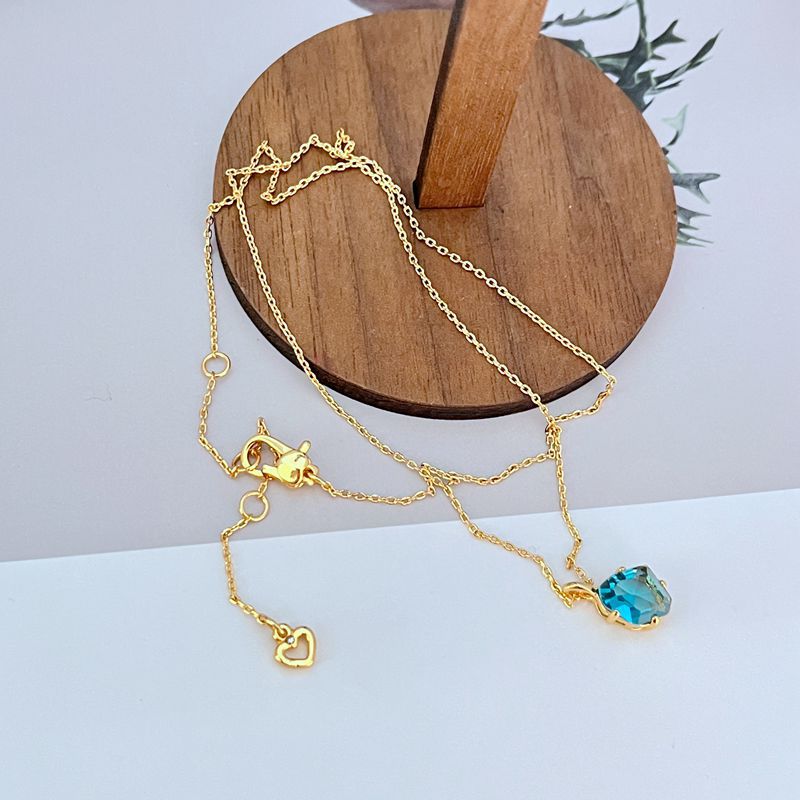 Necklace displayed on a dark background (navy or charcoal) to make the gold and fuchsia gemstone pop. Alt: “Kate Spade Treasure Trove Gold Necklace with Fuchsia Gem – Bold Statement Pendant.”