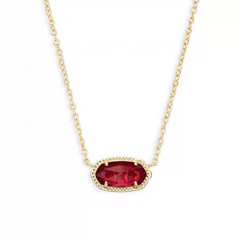 Gold necklace with a red gemstone pendant on a white background