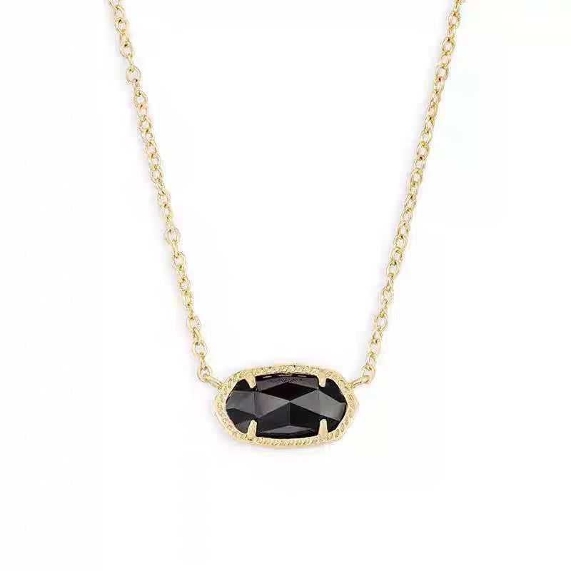 Gold necklace with a black gemstone pendant on a white background