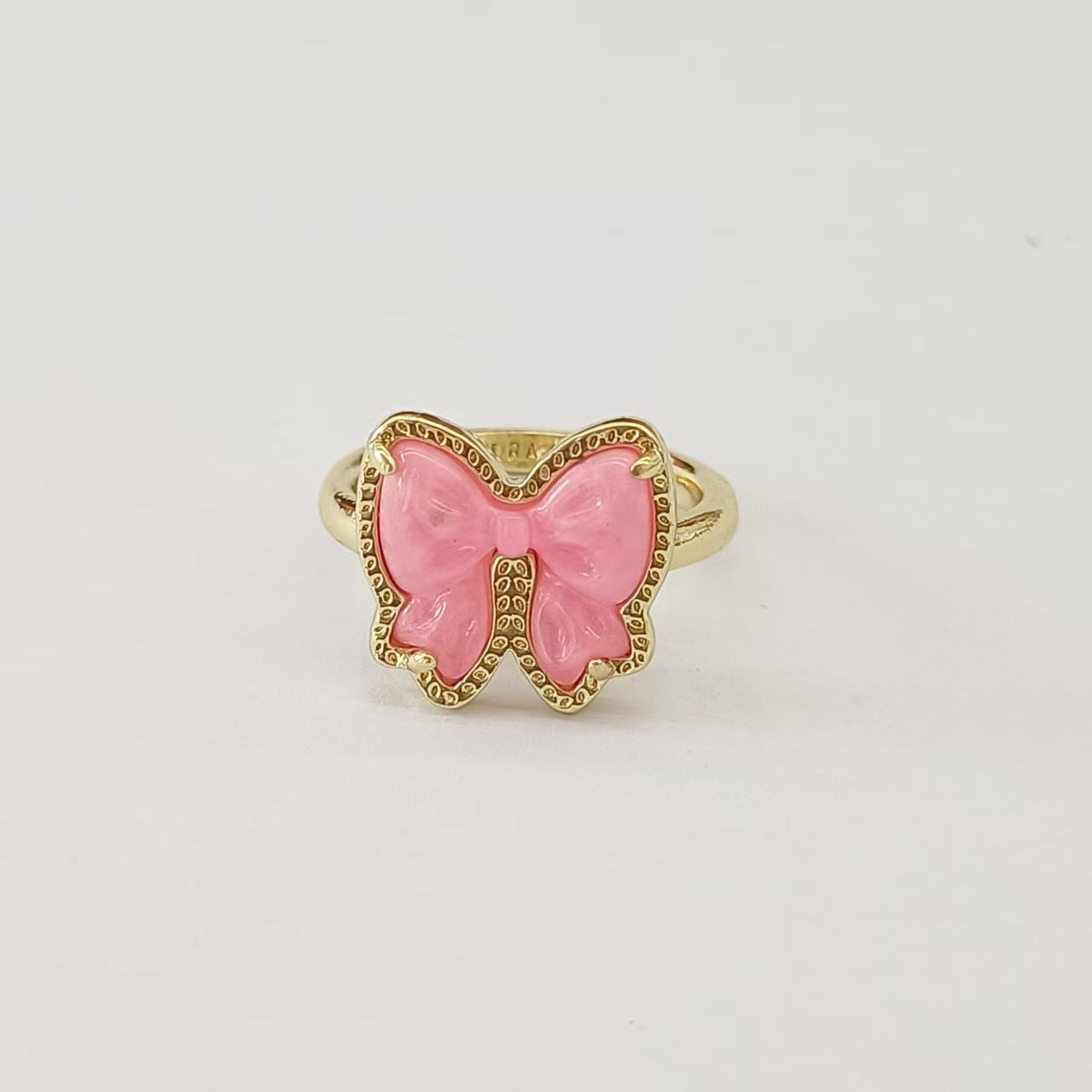 Clean shot of the ring on a finger or ring stand, showcasing the bow detail and the band against a neutral background.