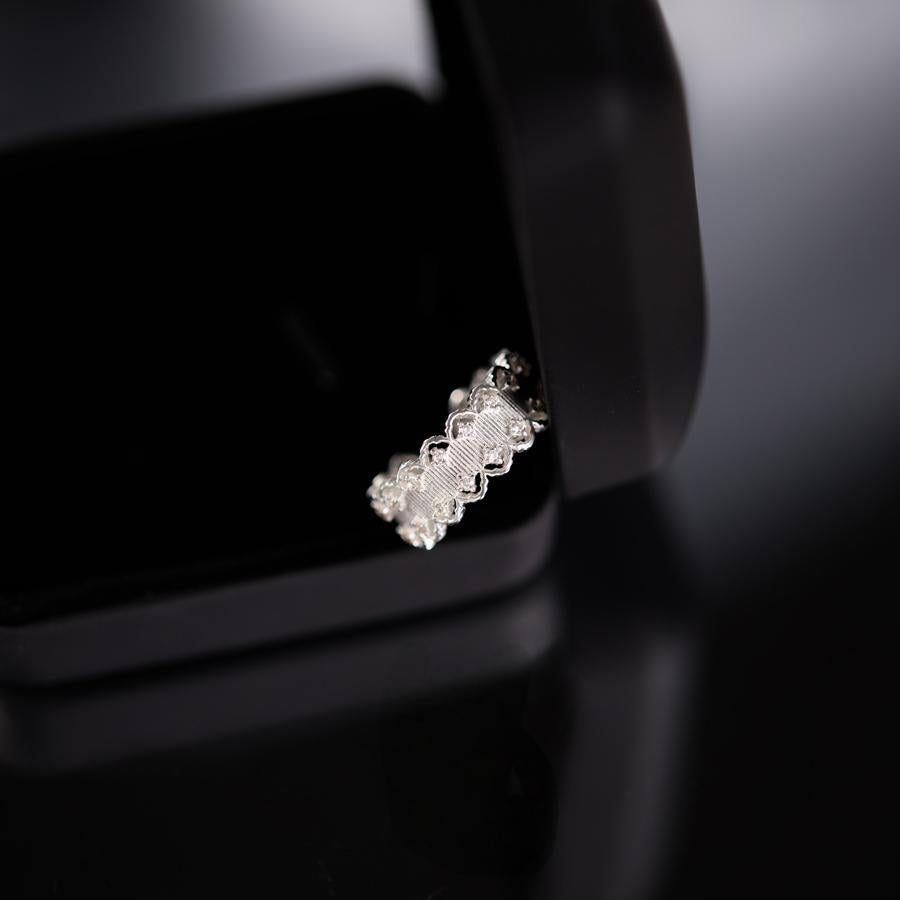Silver earring on a reflective black surface with a blurred background