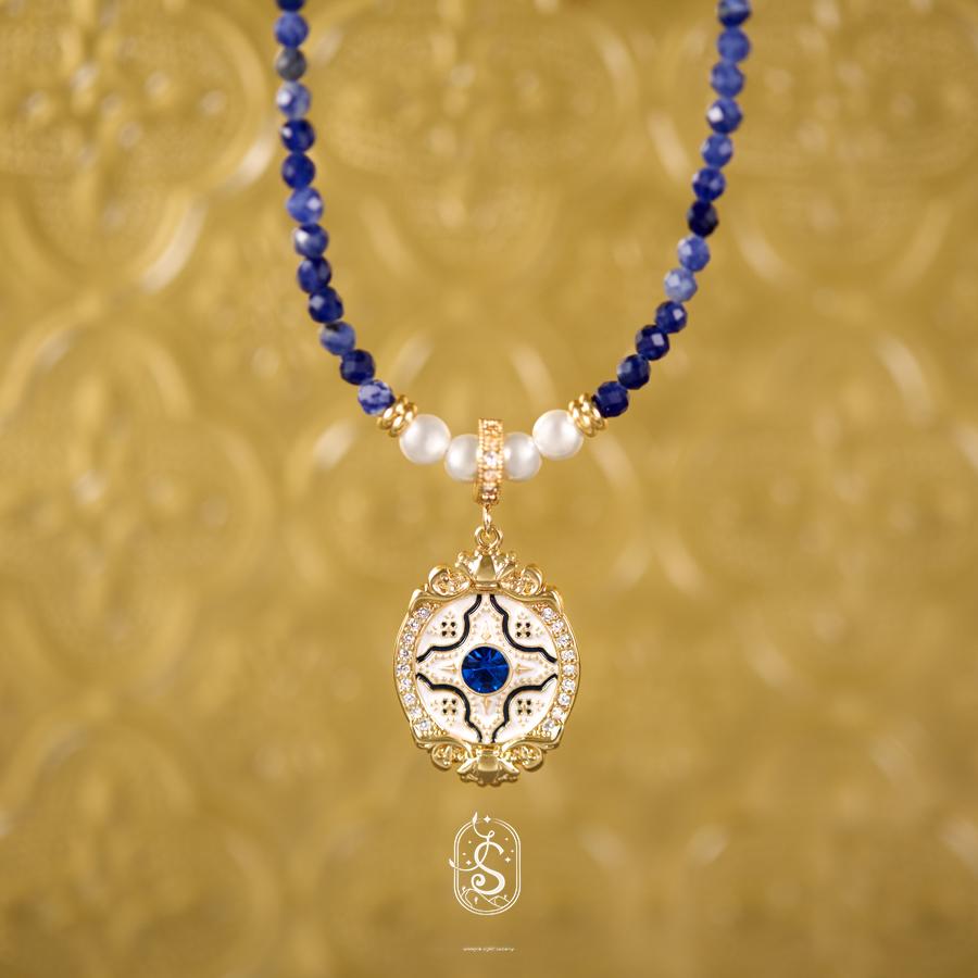 Necklace with blue and white beads and a gold pendant on a gold background