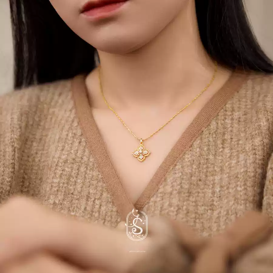 Woman wearing a gold necklace with a detailed pendant, blurred background