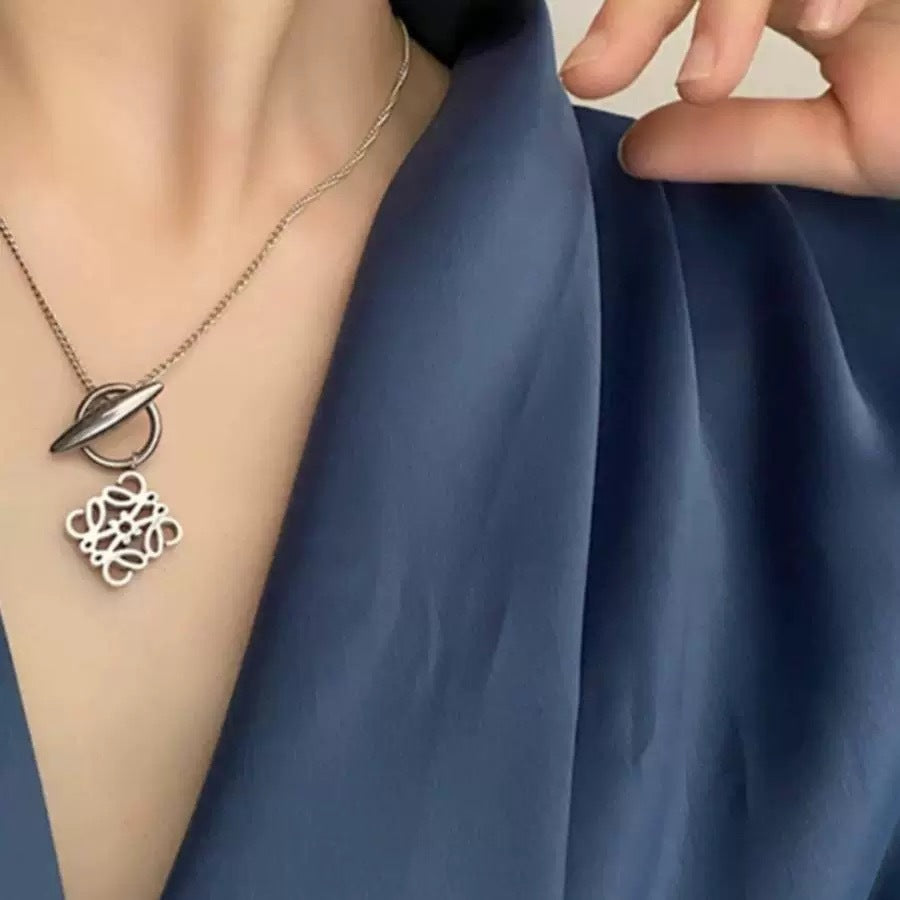 A model with a minimalist aesthetic wearing the necklace over a simple crewneck or blouse, showcasing its understated elegance.