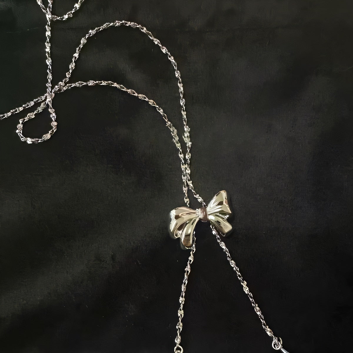 Silver necklace with a bow pendant on a dark background