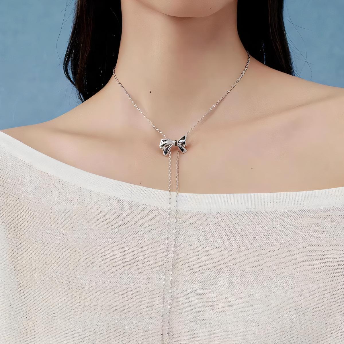 Necklace with a bow pendant worn by a model against a blue background