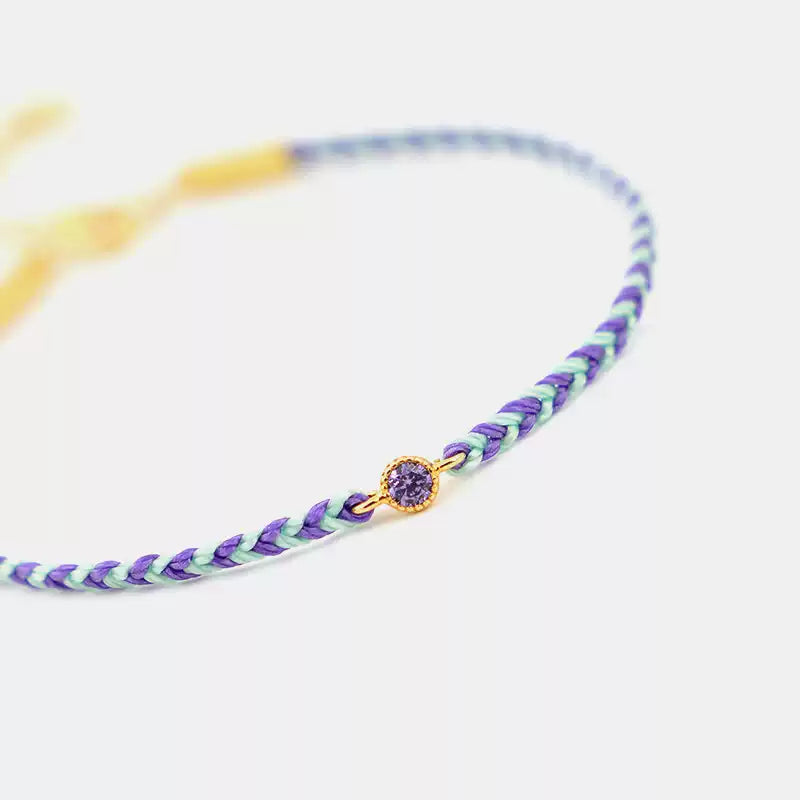 Braided bracelet with a purple bead on a white background