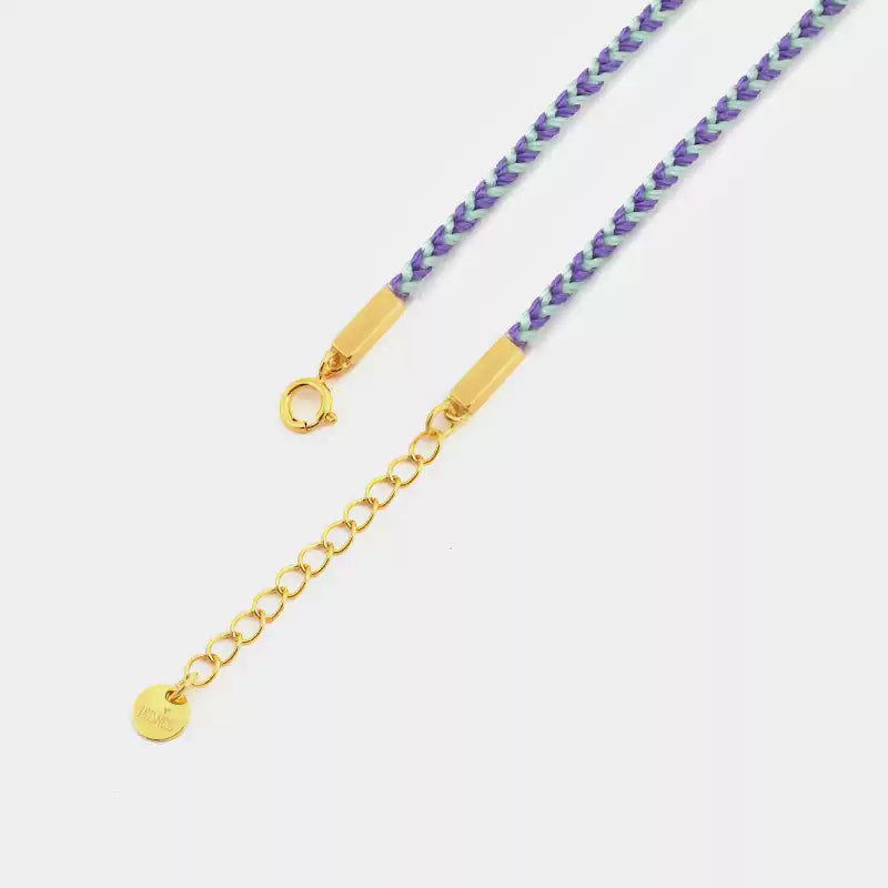 Gold chain necklace with purple beads on a light gray background