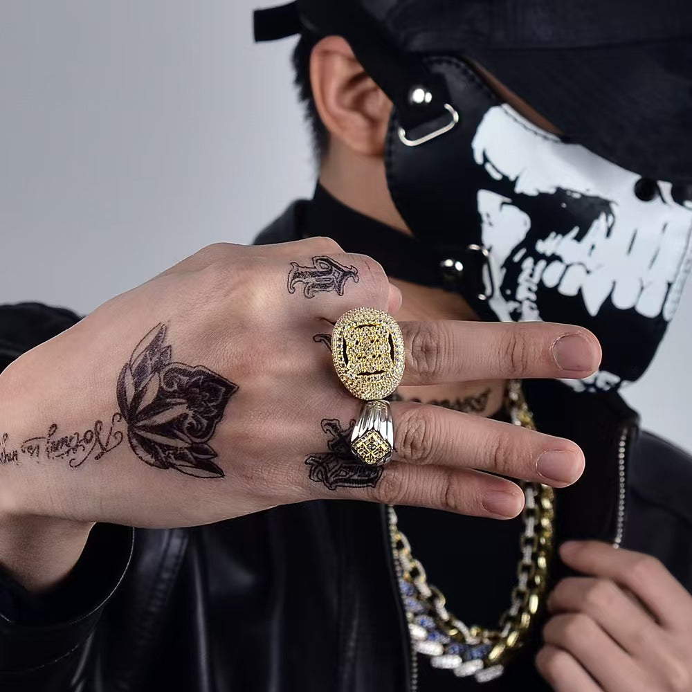 Person wearing multiple rings and showcasing tattoos on fingers with a dark background
