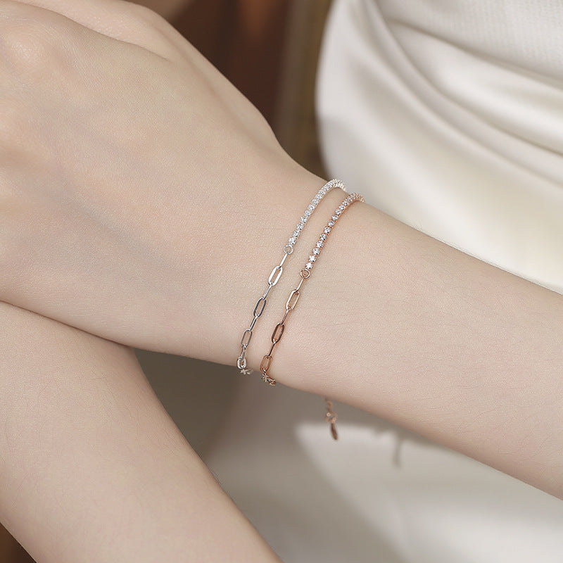 Two delicate bracelets on a wrist against a neutral background