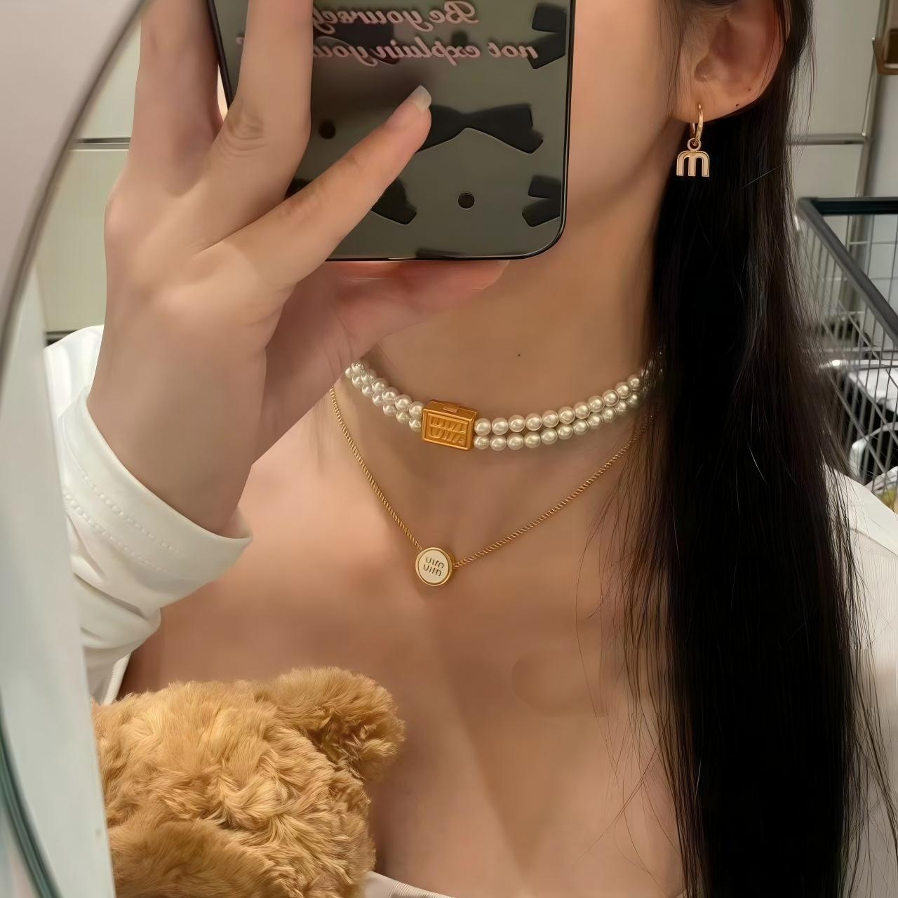 A full-outfit shot of a confident, fashion-forward woman in a contemporary urban setting, showcasing the necklace as the key accessory that completes a polished look. Alt text: "Fashionable Woman in MIU MIU Statement Necklace for Day-to-Night Style."