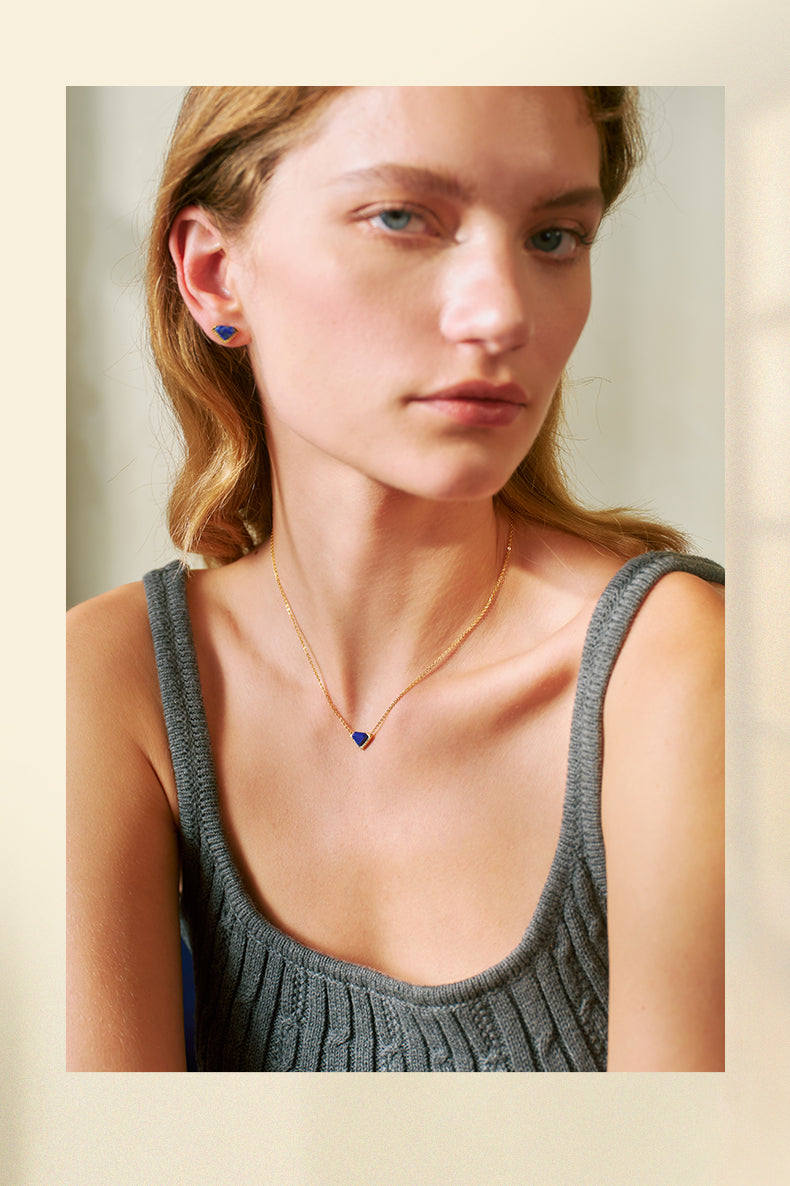 Woman wearing a necklace with a heart-shaped pendant on a neutral background