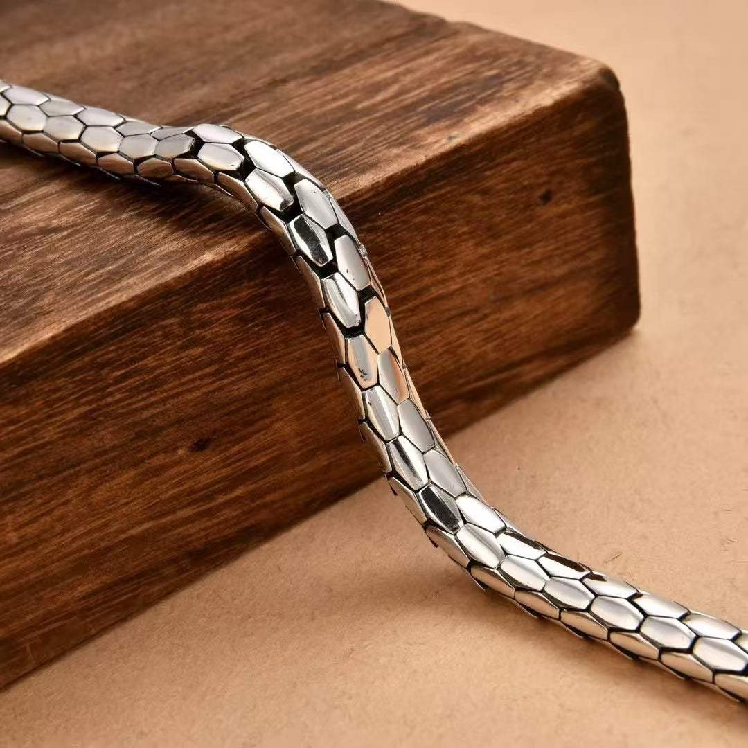 Silver bracelet on a wooden block with a beige background