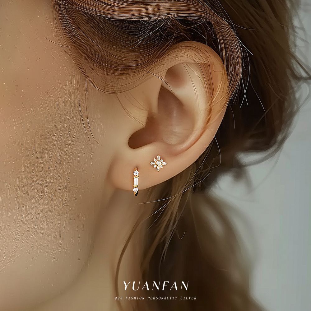 Close-up of an ear wearing two earrings with 'YUANFAN' branding.