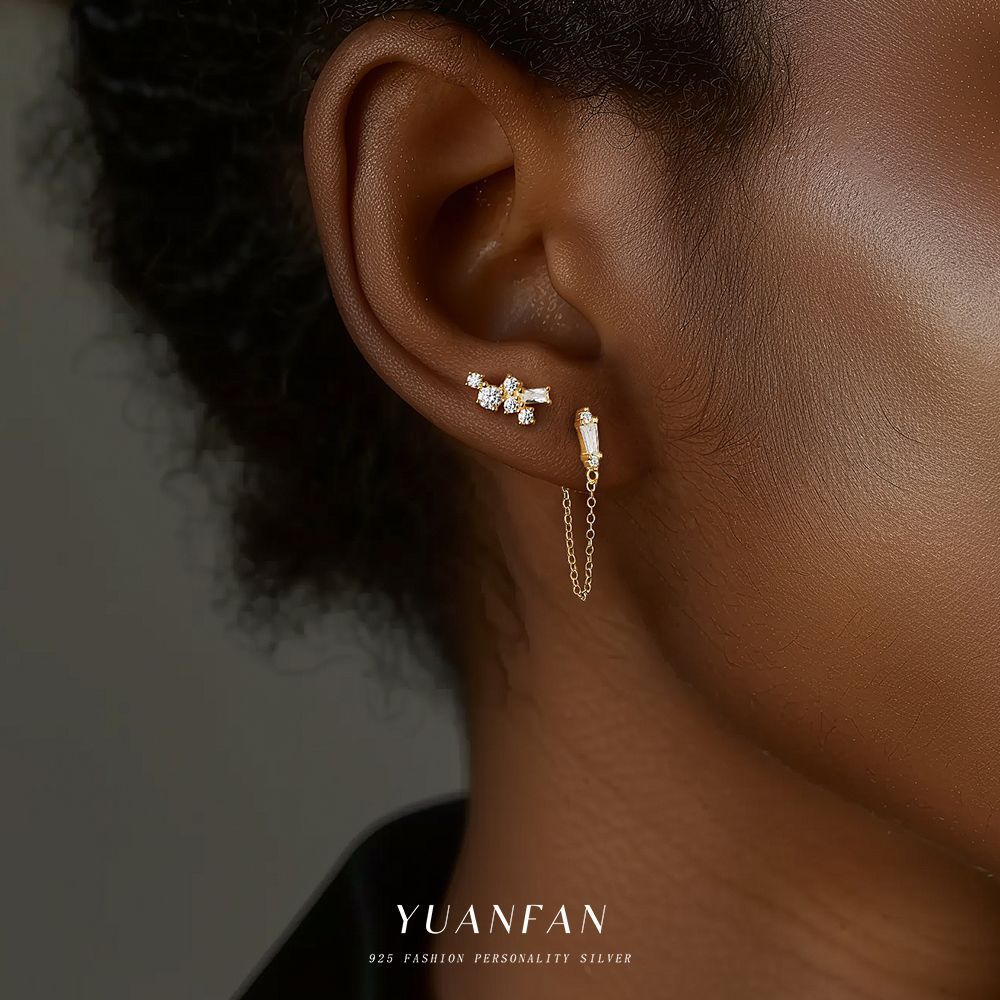 Close-up of an ear wearing gold earrings with 'YUANFAN' branding.
