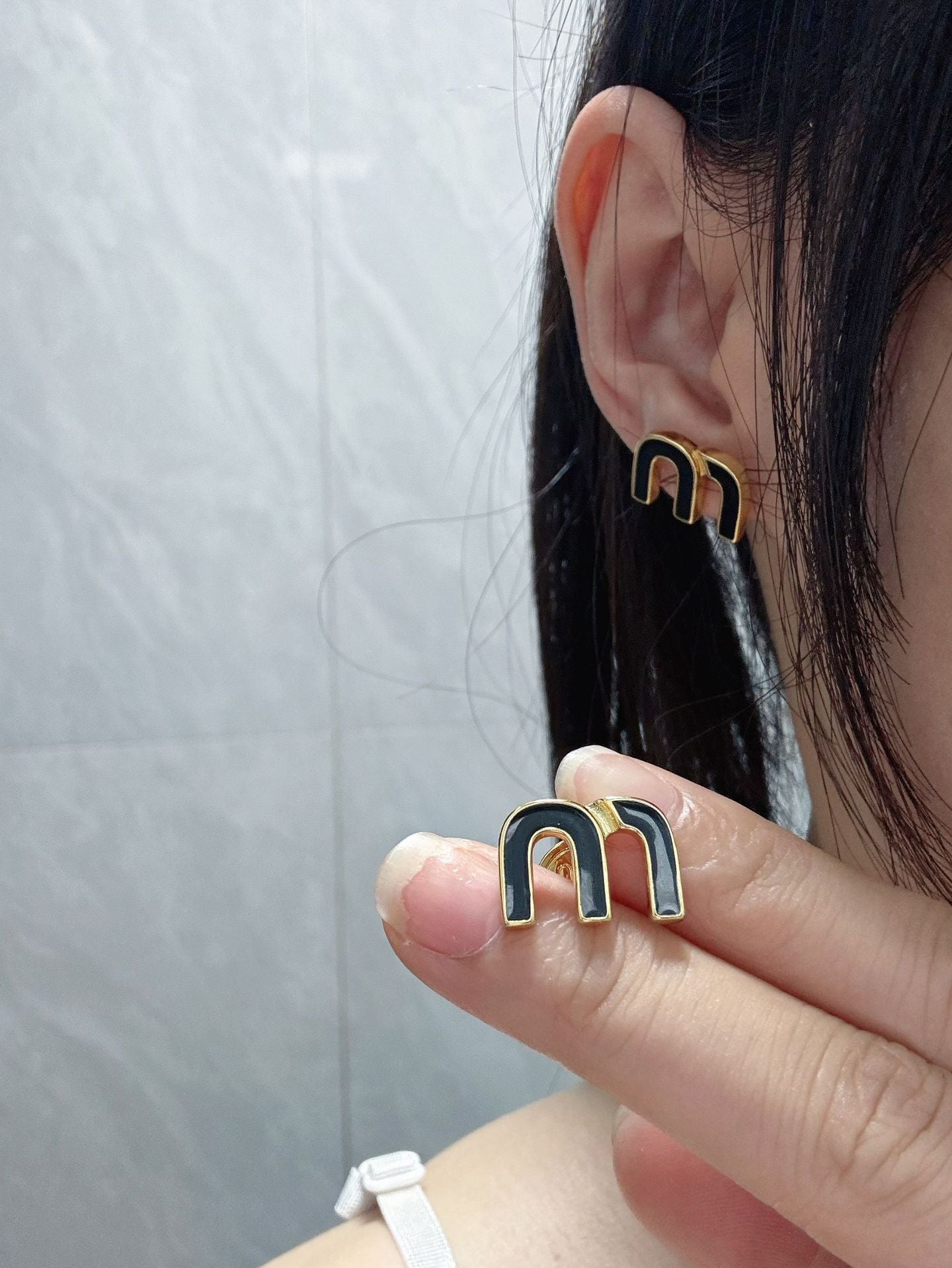 A shot of a model in motion or turning her head, capturing the earrings catching the light and demonstrating their movement and sparkle. Alt text: "Woman Wearing Miu Miu Shimmering Golden Earrings in Motion."