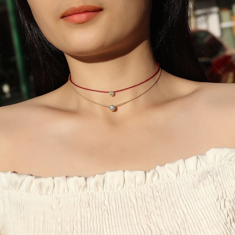 Model wearing the necklace layered with other necklaces in a stack.