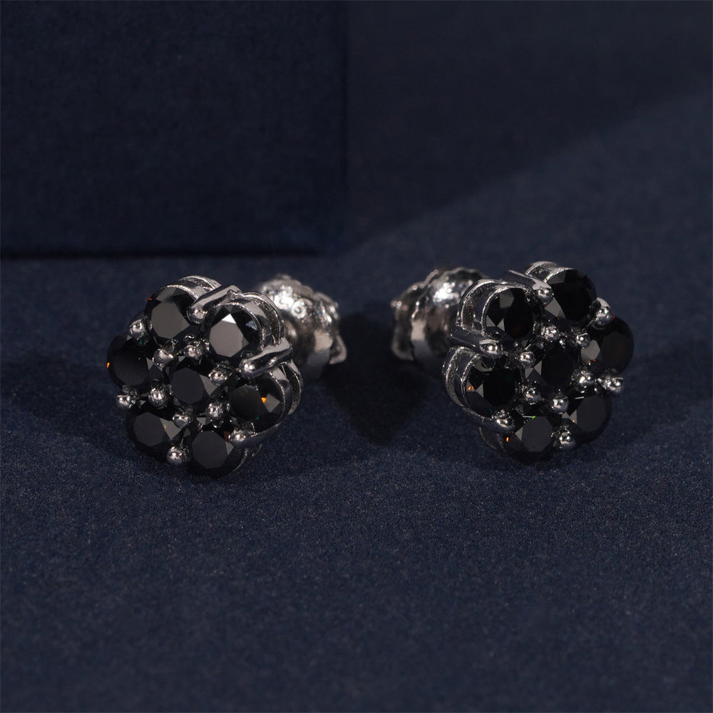 Pair of black and silver earrings on a dark blue fabric background