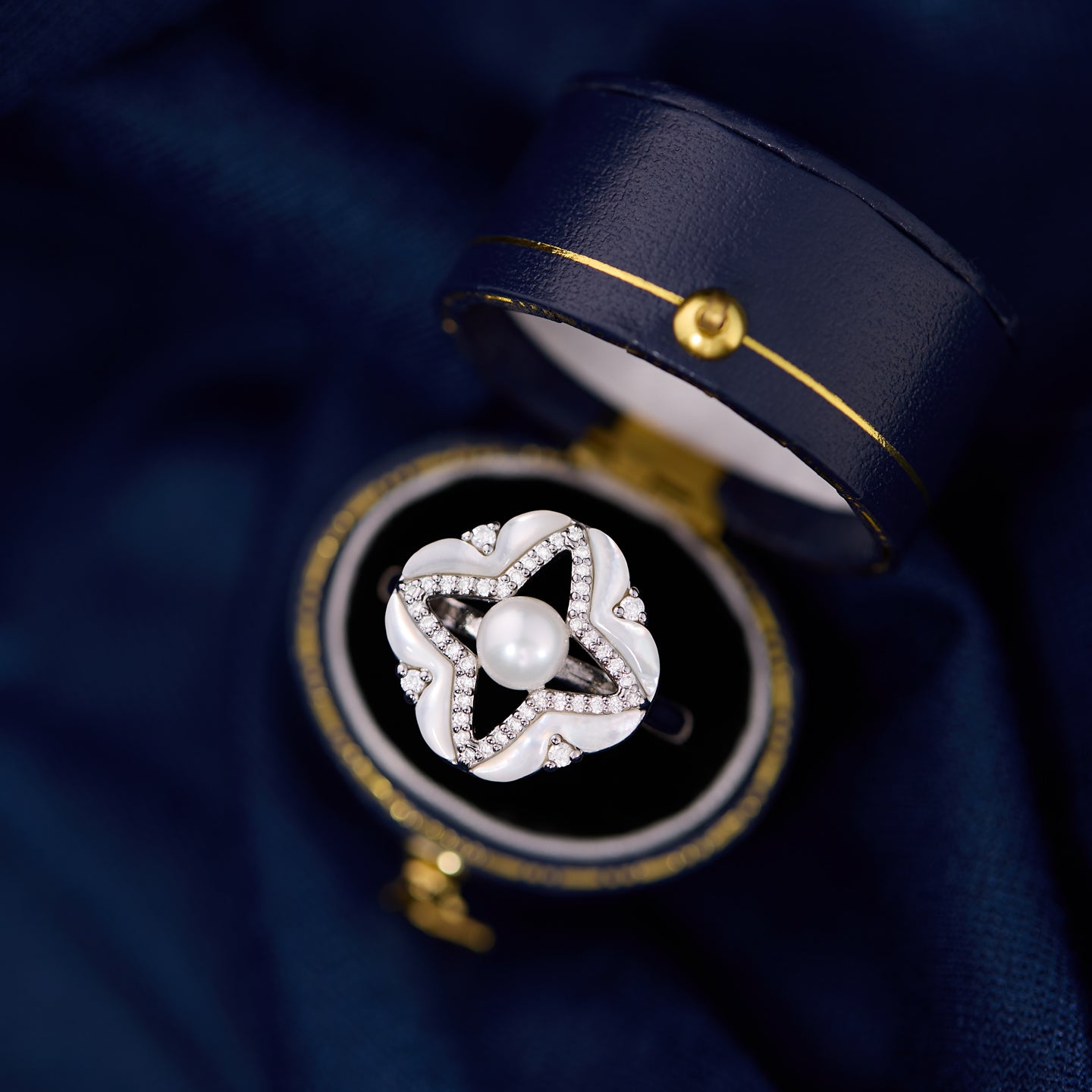 Silver ring with a pearl in an open jewelry box on a dark blue background