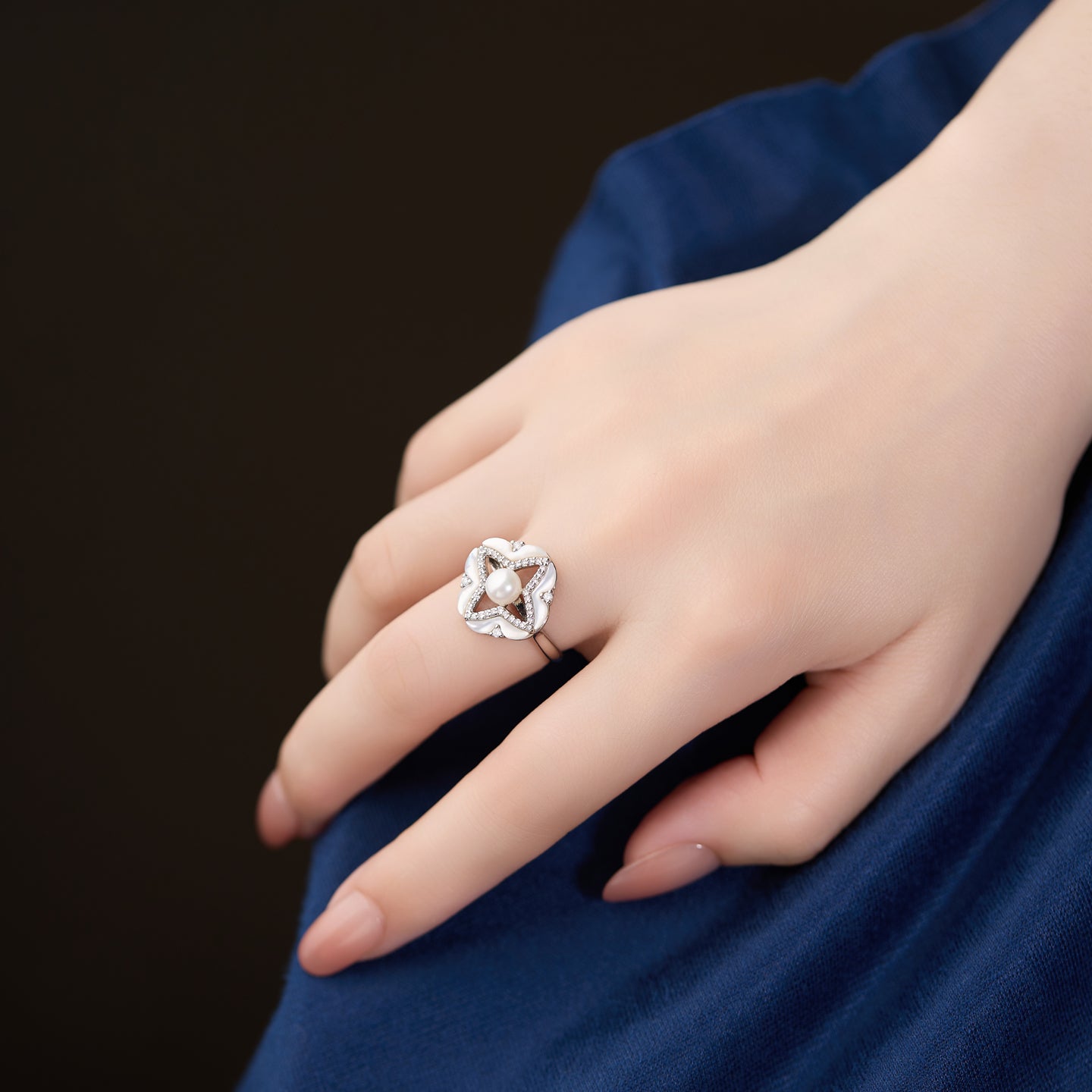 Hand wearing a silver ring with a dark background