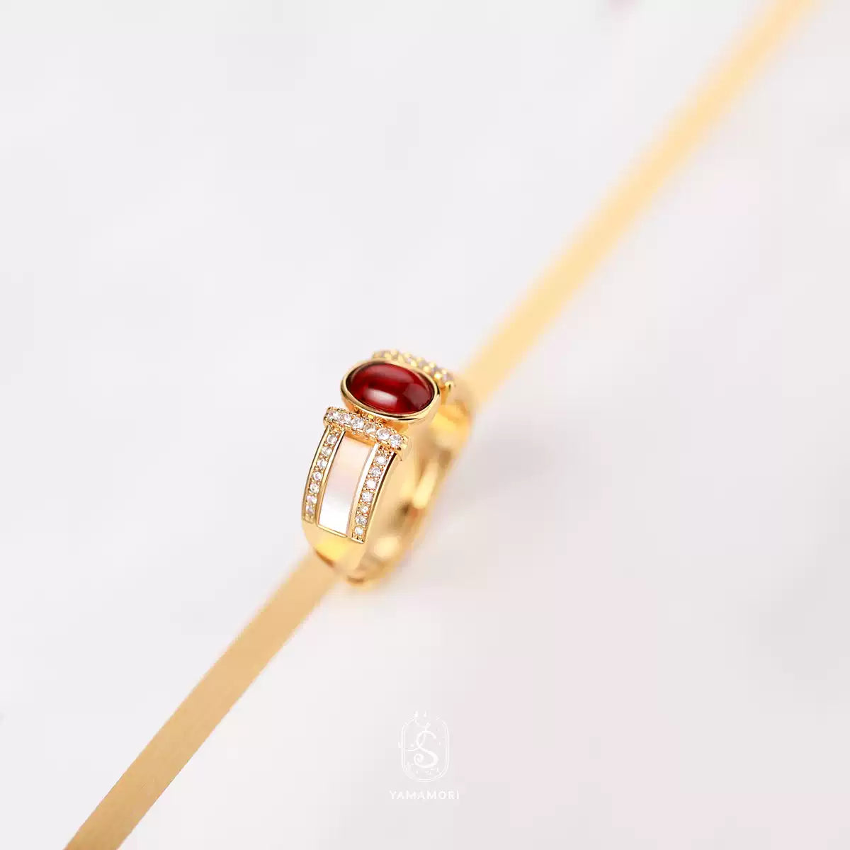 Gold necklace with a red gemstone on a white background