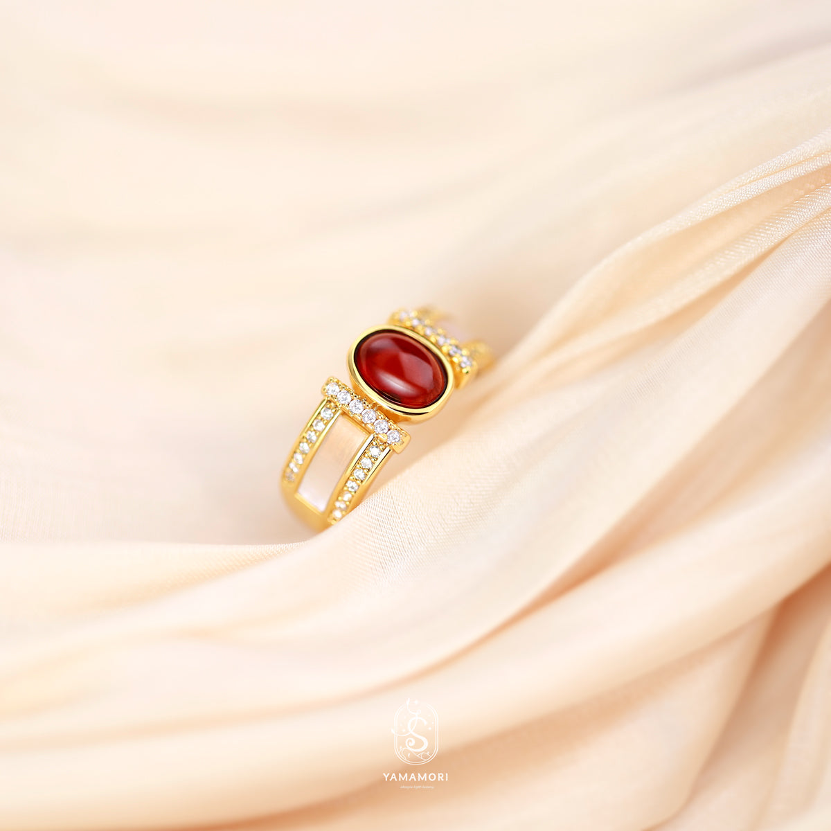 Gold ring with a red gemstone on a beige fabric background