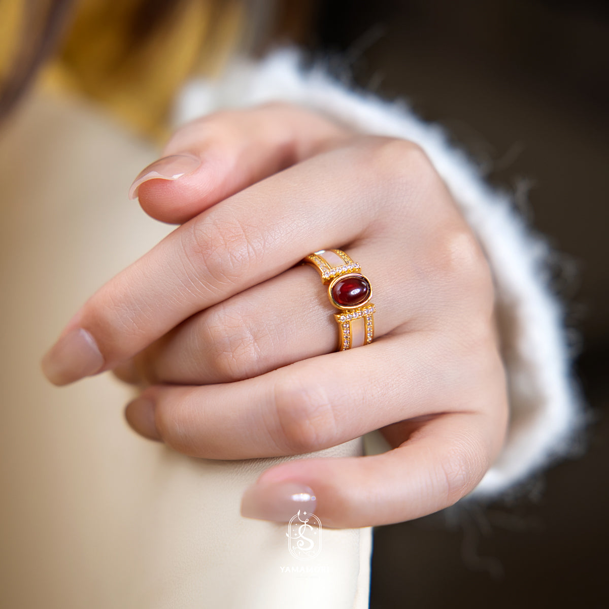 Gold ring with a red gemstone on a person's finger