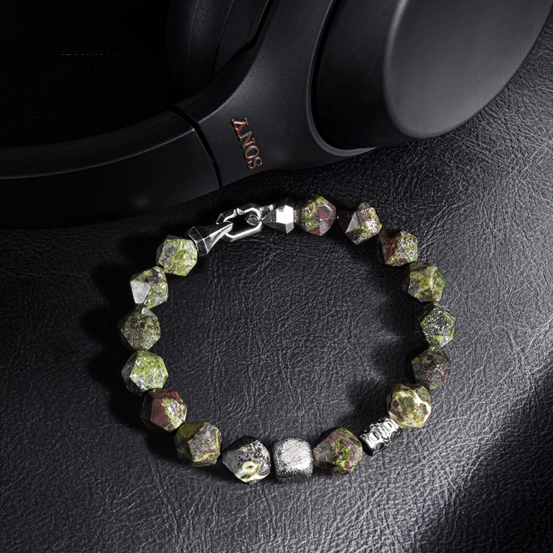 Bracelet with green beads on a black leather surface
