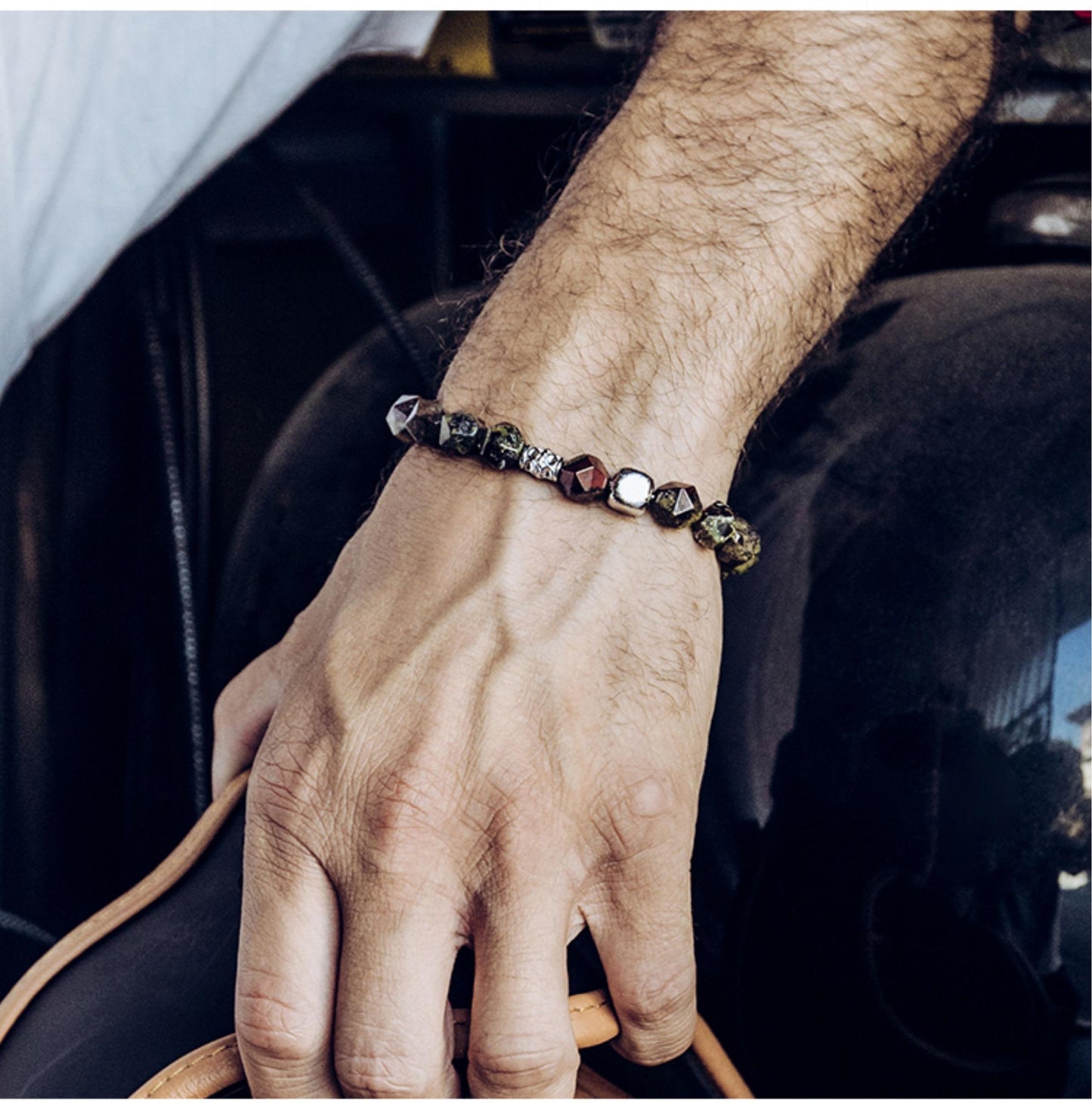 Hand wearing a beaded bracelet with a blurred background