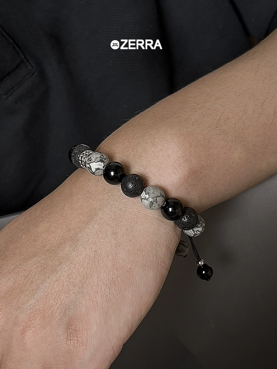 Bracelet with black and gray beads on a wrist, Zerra brand visible
