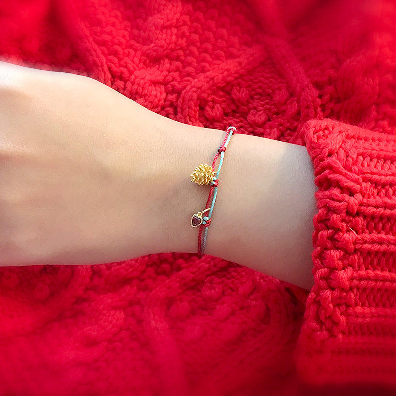 A festive yet refined piece that blends minimalist elegance with warm holiday tones. Handwoven red and green rope embraces a gold-plated 925 silver pinecone charm