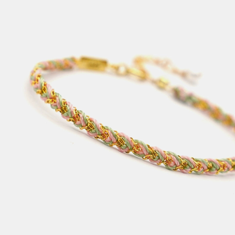 Bracelet with gold and multicolor braided design on a white background