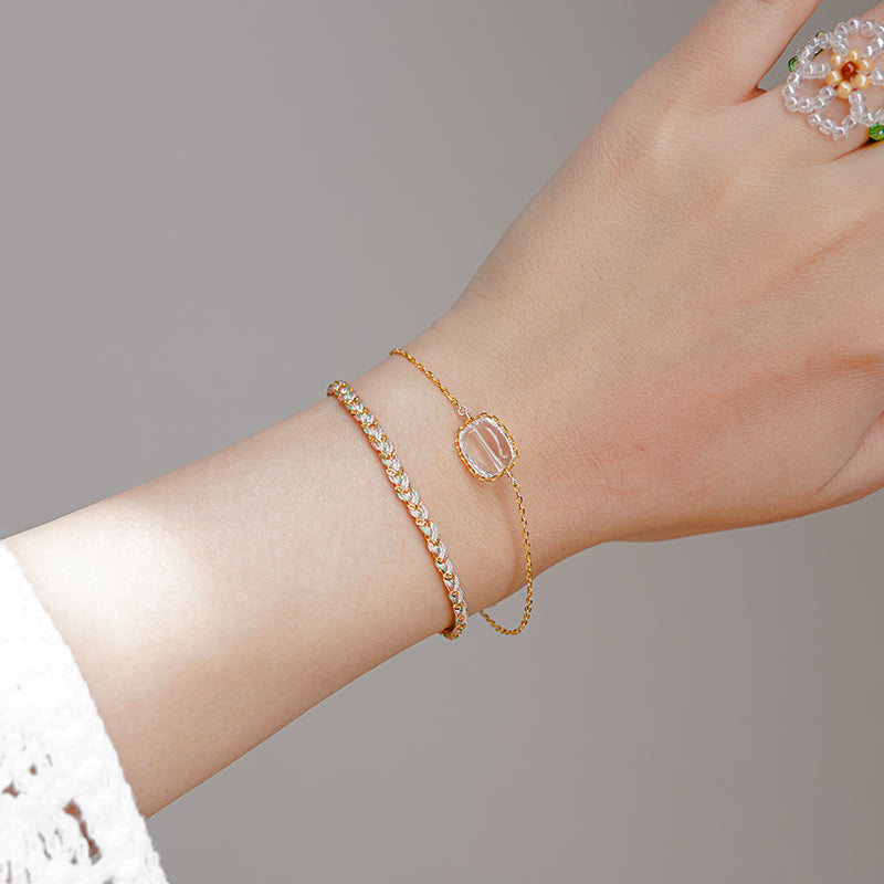 Gold bracelet on a wrist with a neutral background