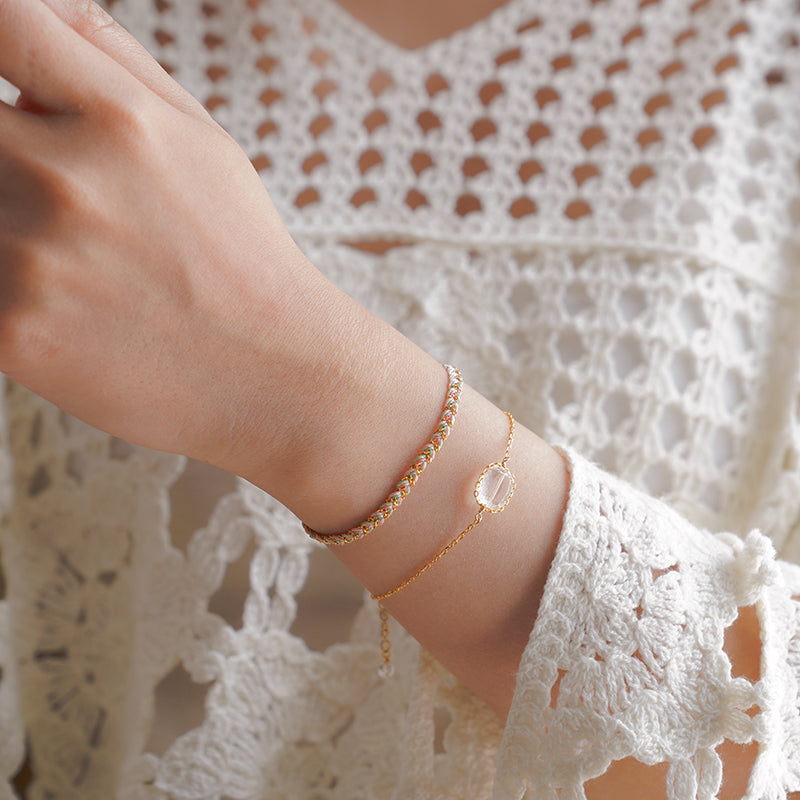 Gold bracelet on a wrist with a white lace garment in the background