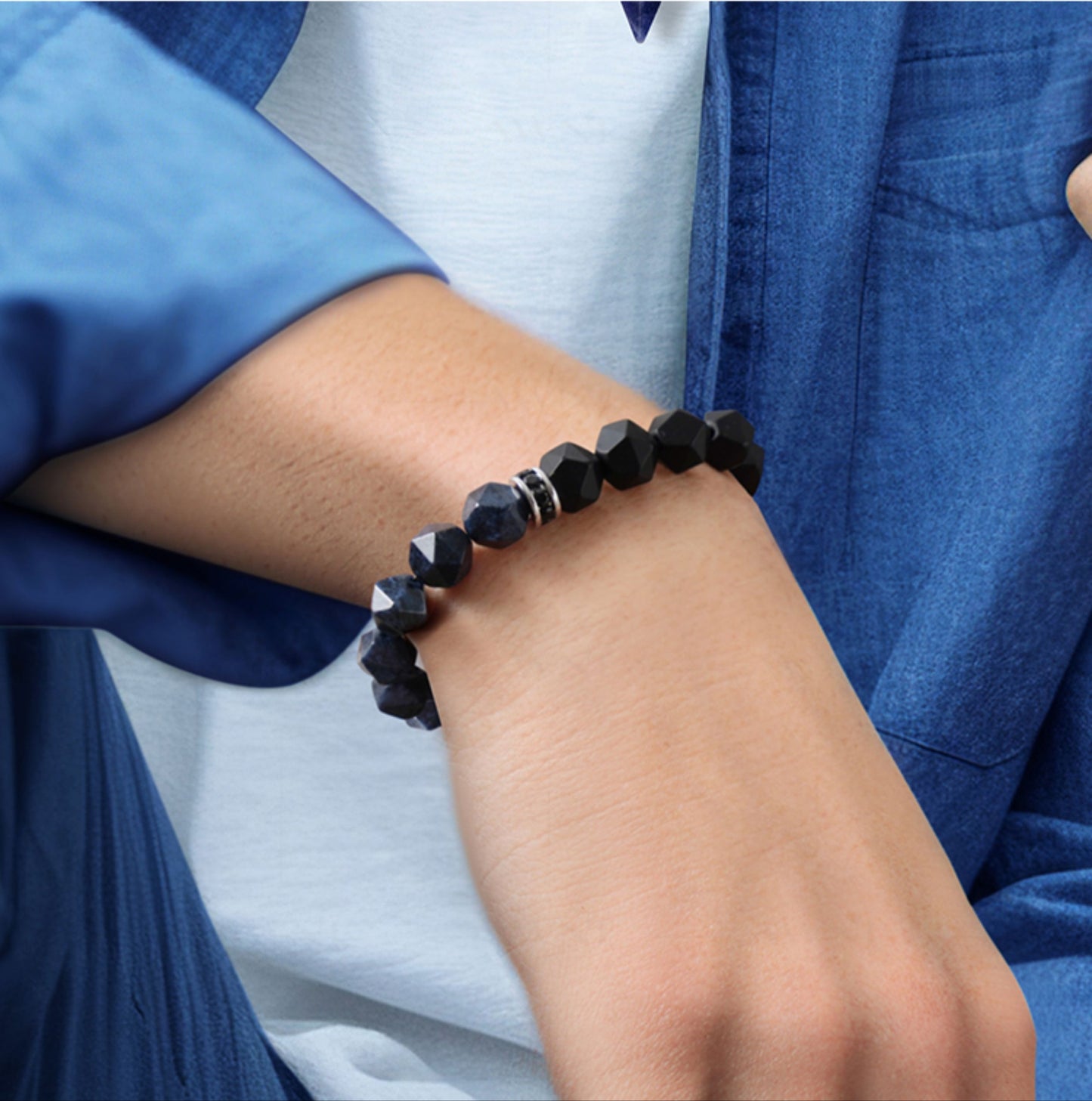 Person wearing a black beaded bracelet on a white background