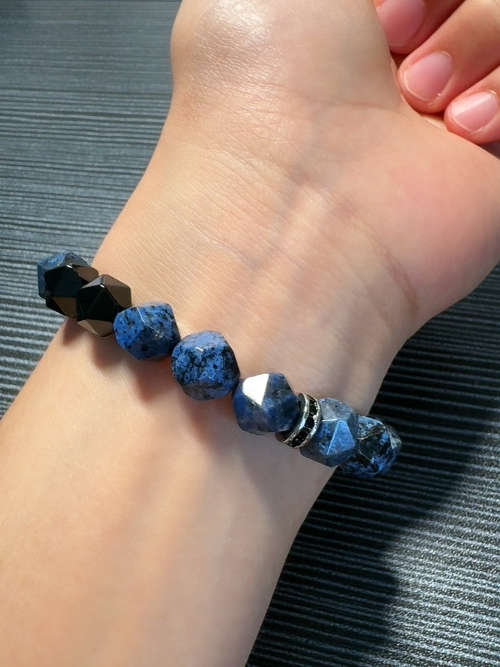 Blue beaded bracelet on a wrist with a gray textured background