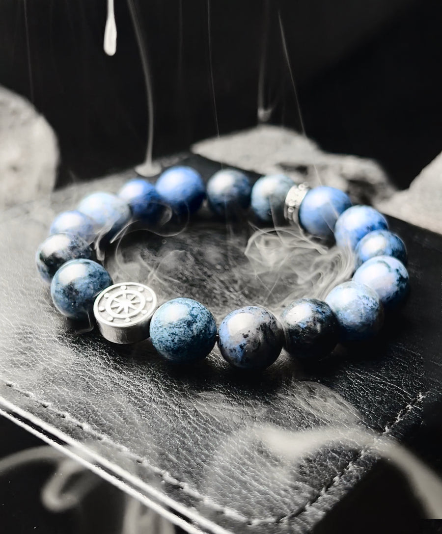 Blue beaded bracelet with a silver charm on a dark surface