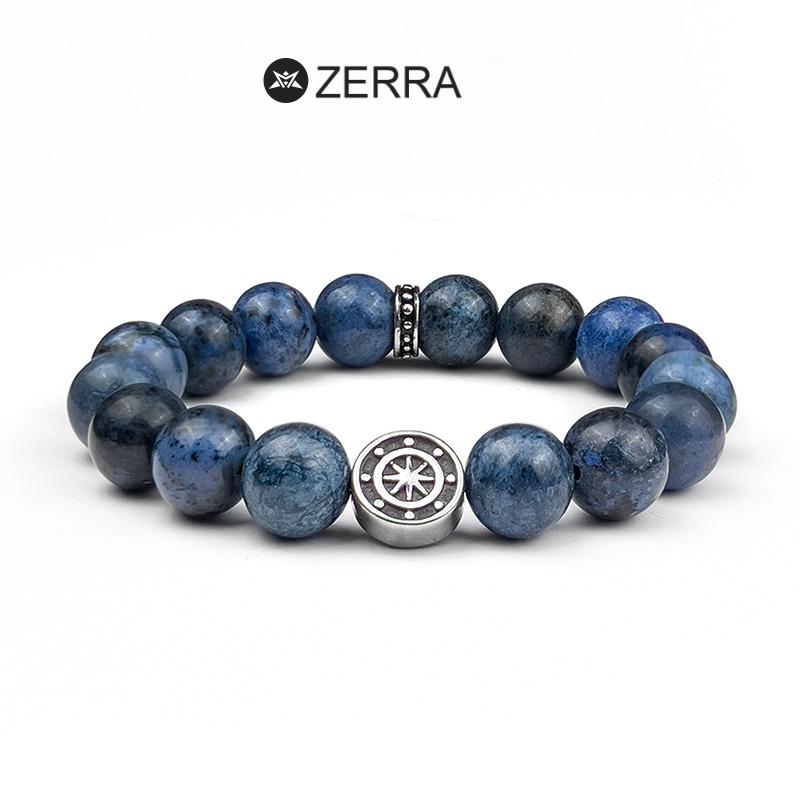 Blue beaded bracelet with a silver charm on a white background, featuring the Zerra brand.